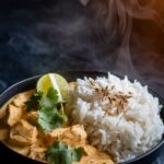 Fluffy basmati rice next to creamy coconut chicken curry in a black bowl